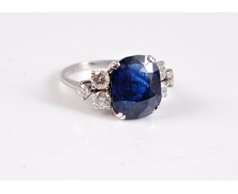 An 18ct sapphire and diamond ring, the old cushion cut sapphire, approx. 11.6 x 9.5 x 5.3mm, in double corner claws, set to e
