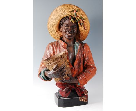 A large early 20th century Goldscheider style Austrian painted terracotta pedestal bust of a black boy, modelled smiling and 