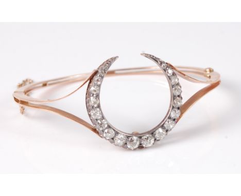 A yellow metal and diamond set hinged bangle, probably converted from a brooch, arranged as a crescent C set with twenty grad
