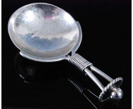 An Arts & Crafts silver caddy spoon, having a circular hammered bowl and triform wirebound stem with disc terminal and ball f