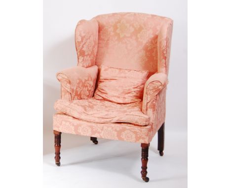 A late Georgian mahogany framed wing armchair, the whole later upholstered in a pink silk floral damask, raised on ring turne