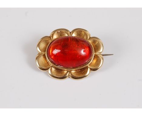A fire opal brooch, the oval fire opal cabochon being collet mounted with closed back and a broad scalloped border, all in un