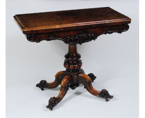 A Victorian figured and carved walnut pedestal card table, the fold-over top having a moulded edge and opening to reveal baiz