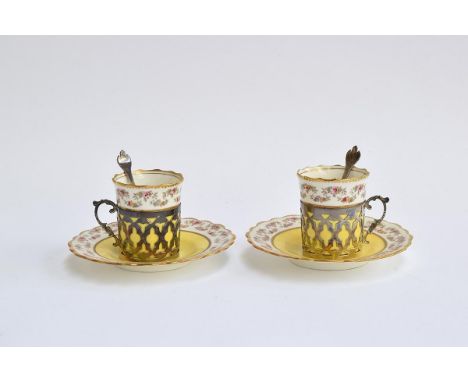 A pair of Aynsley coffee cans and saucers, the cans set within pierced silver holders with scroll handle, hallmarked for Jame