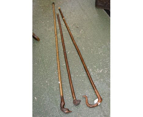 A shepherd's crook walking stick; a walking stick with carved otter's head; another with a bird's head (3)