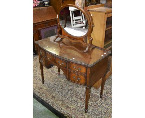 A Reproduction Bow front kneehole dressing table, tapering supports;  a oval dressing table mirror (2)