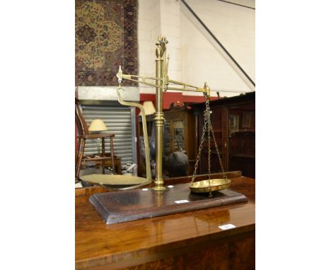 A set of brass balance scales, mahogany plinth stand 