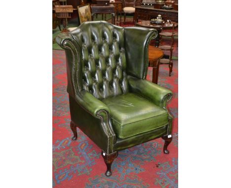 A deep button high back green leather armchair