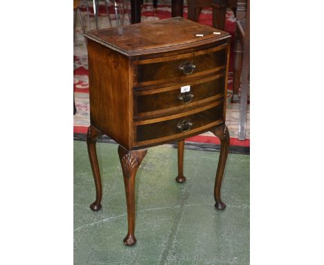 A reproduction bow front bedside cabinet, walnut quarter veneered crossbanded top, three drawers, brass batwing escutcheons, 