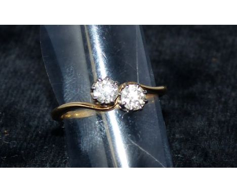 A yellow metal dress ring set with 2 diamonds in crossover setting, stamped '18'