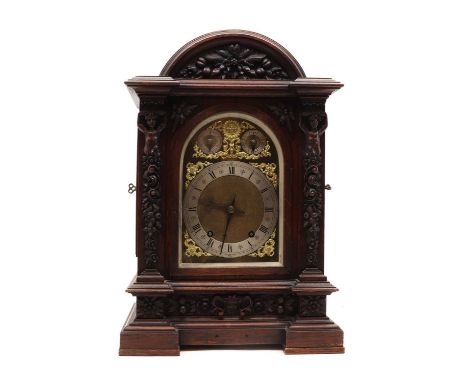 A large late Victorian oak mantel clock,the arched case carved with scrolls, fruiting foliage, herms, flower heads and a mask