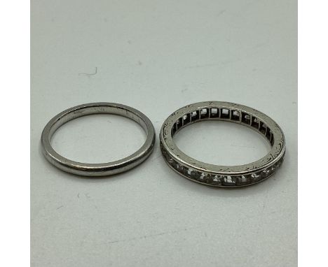 Two unmarked white metal rings. A diamond channel set diamond eternity ring together with a wedding band. Size K. 4.22g. 