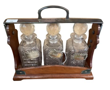 A mahogany cased tantallus, with patent stamp to side, and three hallmarked silver decanter labels, Sherry, Whiskey, Port 