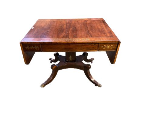 A Regency Brass inlaid kingwood sofa table on square column supports quatrefoil base with gilt brass paw feet and ceramic cas