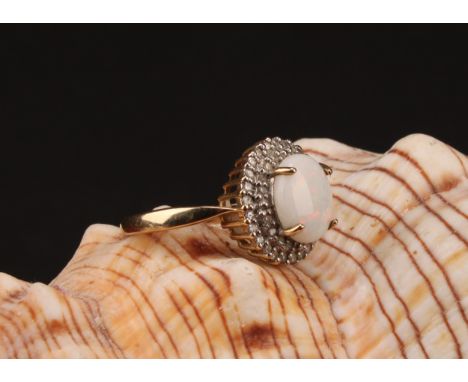 A 9ct gold white opal and diamond cluster ring, consisting of an oval cabochon opal that measures approx. 10mm x 8mm surround