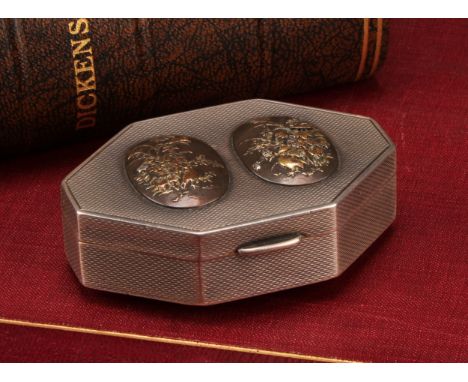 An unusual George V silver lozenge shaped snuff box, applied with Japanese Meiji period menuki type mixed metal panels, on an