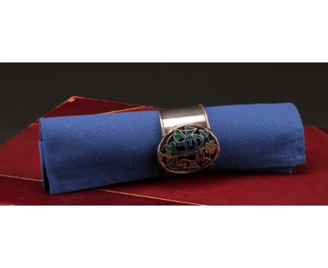 An Arts and Crafts silver and enamel napkin ring, pierced and decorated in polychrome with flowers and a monogram, 5cm diam, 