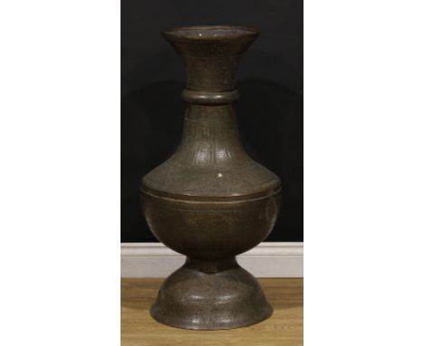 A large Islamic copper floor standing baluster mosque lamp, pierced and chased with Arabic script and Middle Eastern motifs, 