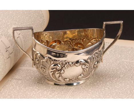 An Edward VII Rococo Revival silver two-handled sugar basin, chased with flowers and foliate scrolls, angular handles, gilt i