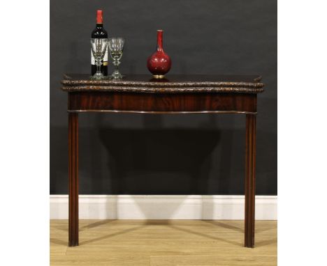 A George III Revival mahogany serpentine card table, in the Chippendale taste, folding top with ribbon-carved edge enclosing 