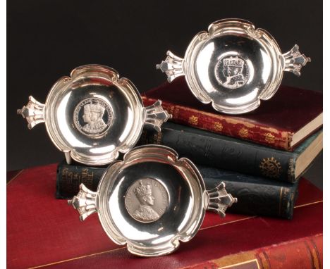 Asprey - a set of three silver shaped circular quaichs, each base inset with a commemorative silver coloured metal medallion,