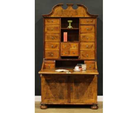 An 18th century German walnut bureau cabinet, architectural pediment above an arrangement of drawers, a fall front door, a lo