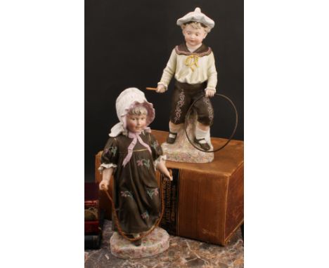 A pair Gebrüder Heubach bisque figures, of a boy and girl at play, he with hoop and stick, she with skipping rope, polychrome