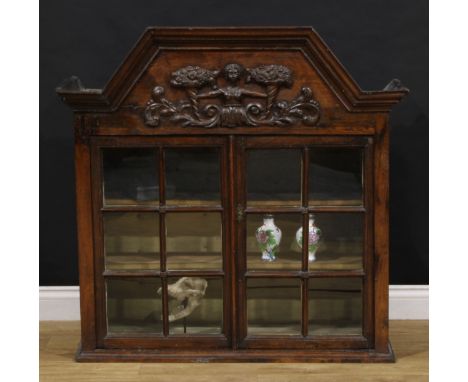 An 18th century Dutch china closet or cabinet, canted arch cresting above a deep frieze carved and applied with a female herm