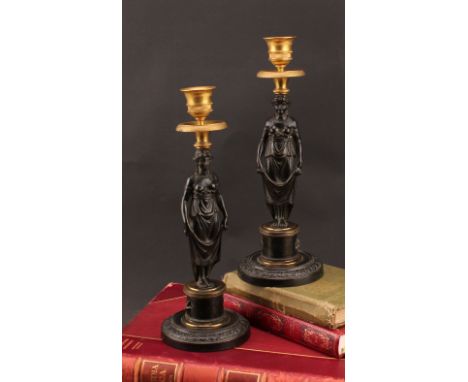 A pair of 19th century Grecian Revival parcel gilt and dark patinated bronze figural candlesticks, circular bases with acanth