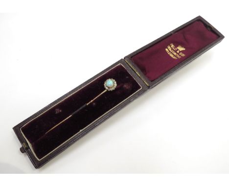 A gold stick pin with an opal and diamond cluster finial