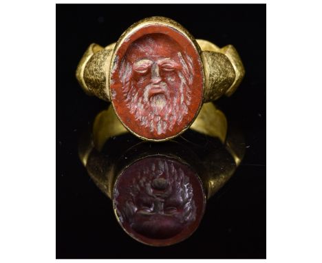 CA. 200 AD. Rare Ancient Roman gold ring; a decorated solid hoop forming an oval bezel; beautifully carved red intaglio stone