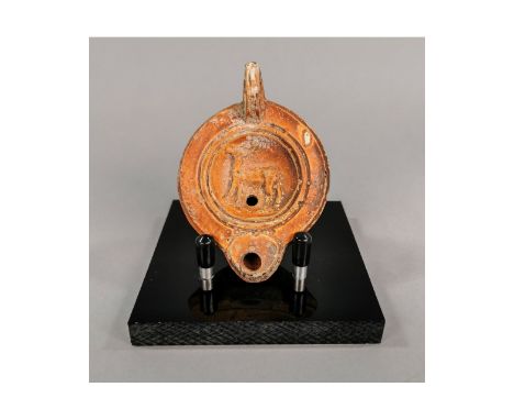 Ca.200-300AD. A nice terracotta oil lamp in deep red burnish finish; the discuss decorated with a deer; ring handle at the ba