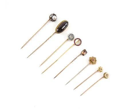 A group of eight stick pins, including a ruby set stick pin, another with a circular black onyx head, both testing as 18 ct, 