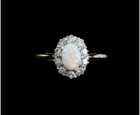 Opal and diamond cluster ring, with a central oval cabochon cut opal measuring 6.8 x 4.9 x 2.3mm, weighing a calculated 0.45 