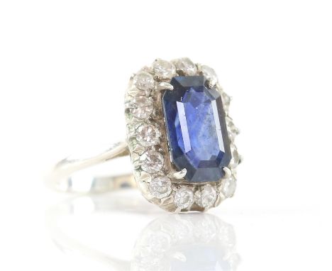 Sapphire and diamond cluster ring, with an emerald cut sapphire weighing an estimated 4.16 carats, surrounded by fourteen rou