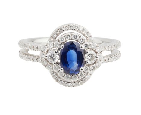 An 18ct white gold sapphire and diamond set cluster ringclaw set with an oval cut sapphire, flanked to either side by a round
