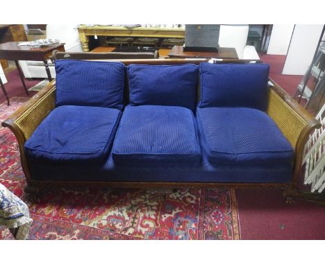 An Edwardian Chippendale style mahogany bergere sofa, with double caning, raised on paw feet 