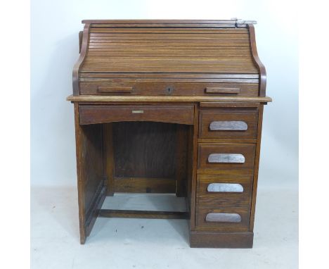 An early 20th century light oak roll top desk, with rubbed makers label, H.111 W.92 D.66cm 