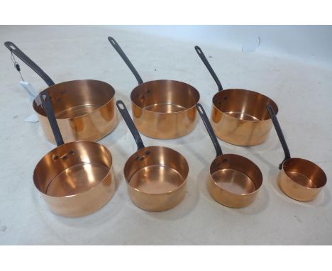 A vintage graduated set of 7 copper saucepans with iron handles 