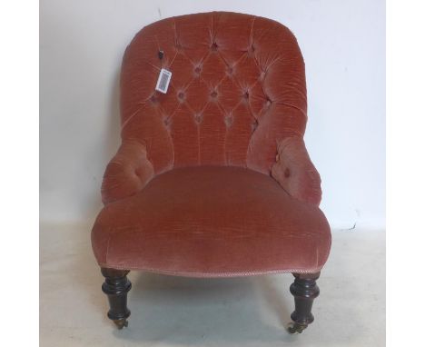 A Victorian velour upholstered button back chair, raised on turned legs and castors 