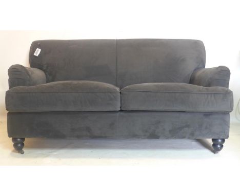 A contemporary grey velour upholstered sofa, raised on turned legs and castors 