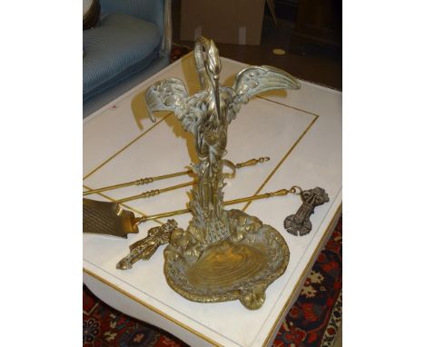 A BRASS FIRESIDE COMPANION, early 20th century, formed as a heron standing by a lily pond, with outstretched wings enclosing 