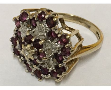 A ruby and diamond cluster ring in the form of a flower, in gold settings. Ring size N