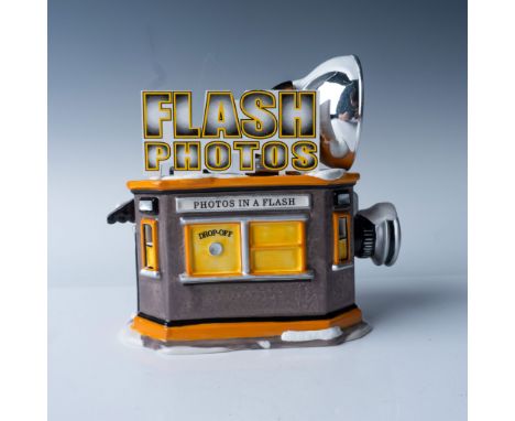 A charming and whimsical addition to the Department 56 Snow Village series, this "Flash Photo Hut" is a delightful ceramic fi