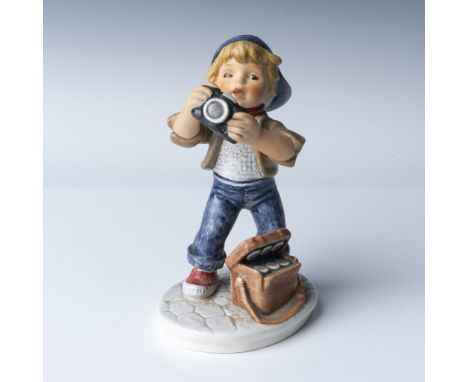 This Hummel Goebel porcelain figurine from the Today's Children series depicts a young boy enthusiastically photographing wit