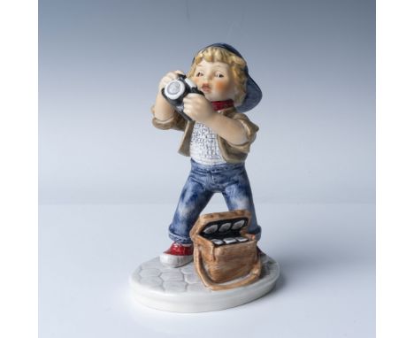 Goebel porcelain figurine titled "Young Photographer," featuring a young boy enthusiastically holding a camera with a bag of 