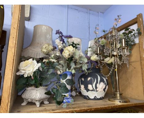 A shelf of artificial flowers and table lamps