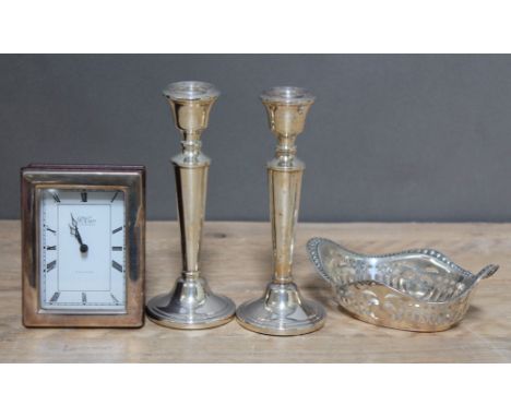 A mixed lot of hallmarked silver comprising a pair of candlesticks, a pierced bon bon dish and a silver framed clock, various