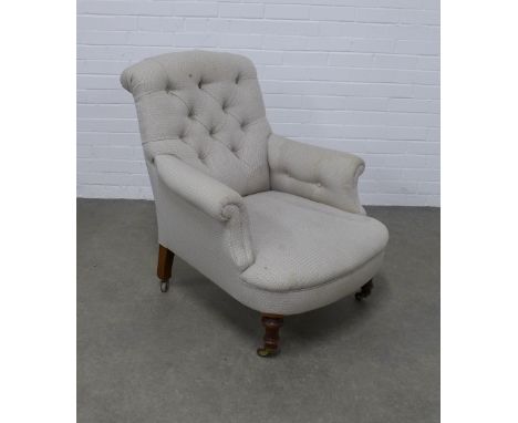 Button back upholstered armchair, scrolled top and arms, long proportioned seat, on turned legs with brass caps and ceramic c
