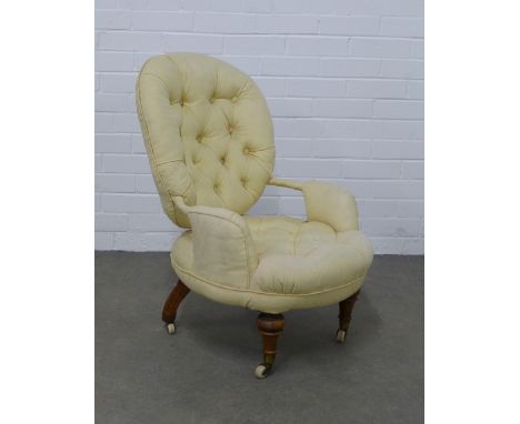A button back upholstered armchair of small proportions, on mahogany legs with ceramic castors,  55 x 78 x 46cm. 